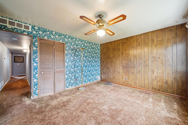 carpeted spare room featuring ceiling fan, visible vents, wallpapered walls, and baseboards