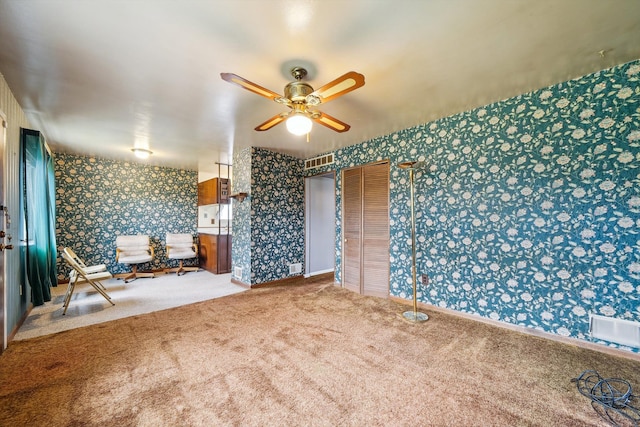 spare room with ceiling fan, visible vents, baseboards, carpet, and wallpapered walls