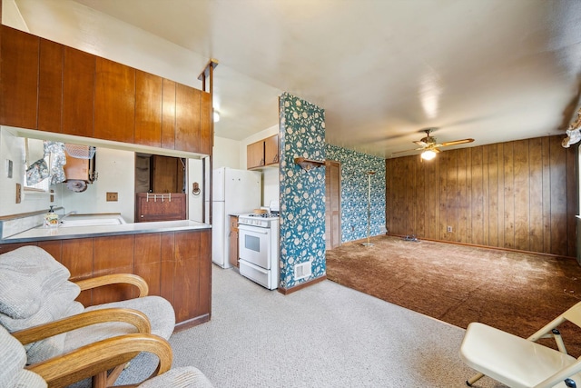 kitchen featuring a ceiling fan, white appliances, light colored carpet, brown cabinets, and a sink