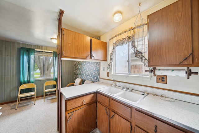 kitchen with light countertops, brown cabinetry, plenty of natural light, and a sink