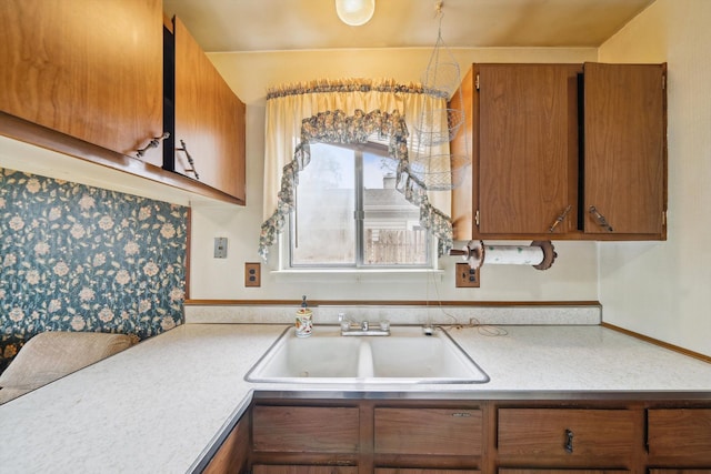 kitchen featuring light countertops, brown cabinets, and a sink