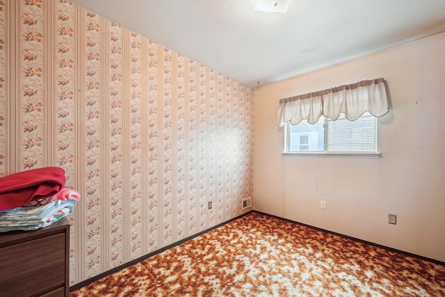 unfurnished bedroom featuring baseboards, carpet flooring, wallpapered walls, and visible vents