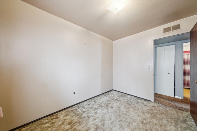 carpeted spare room featuring visible vents and baseboards