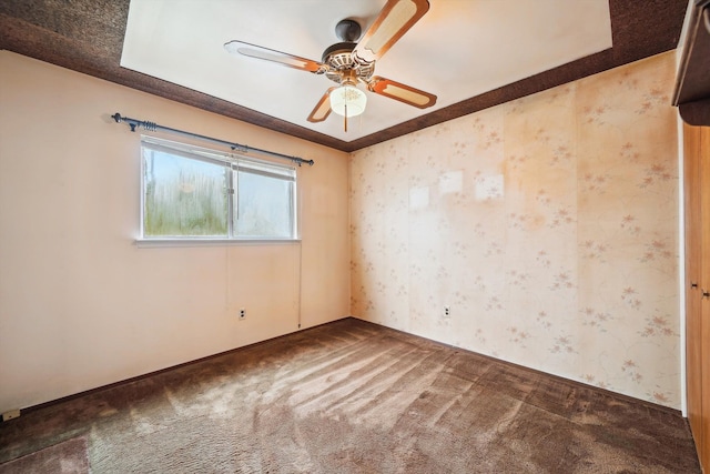 carpeted spare room featuring a ceiling fan and wallpapered walls