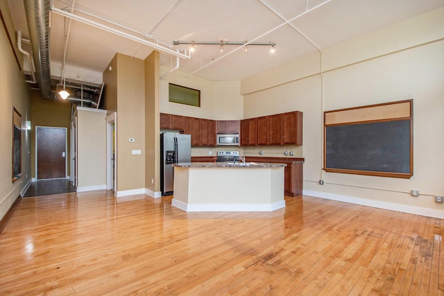 kitchen with appliances with stainless steel finishes, rail lighting, open floor plan, and a towering ceiling