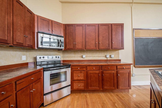 kitchen featuring dark countertops, appliances with stainless steel finishes, and light wood-type flooring