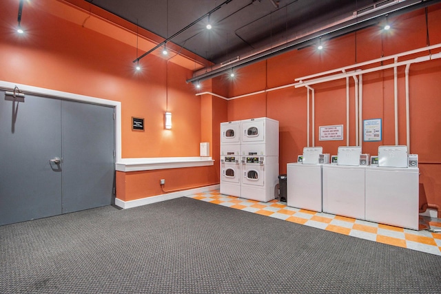 common laundry area with rail lighting, stacked washing maching and dryer, and washing machine and dryer
