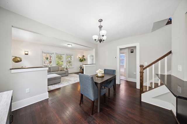 dining area with baseboards, a notable chandelier, wood finished floors, and stairway