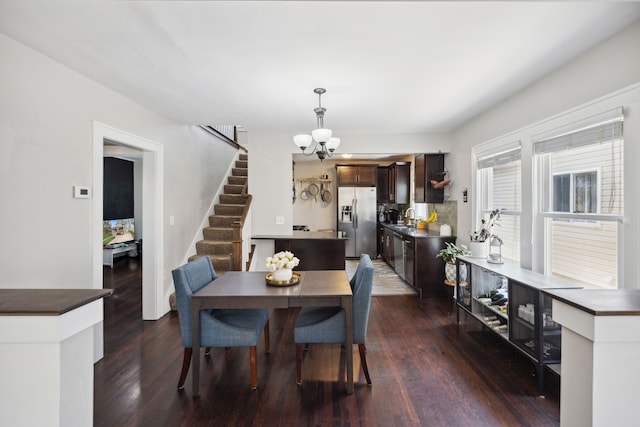 dining space featuring dark wood-type flooring, a notable chandelier, and stairway