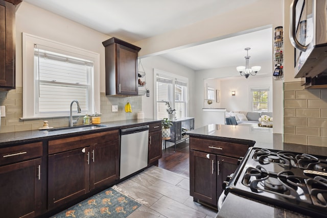 kitchen featuring dark brown cabinetry, a notable chandelier, appliances with stainless steel finishes, a sink, and tasteful backsplash