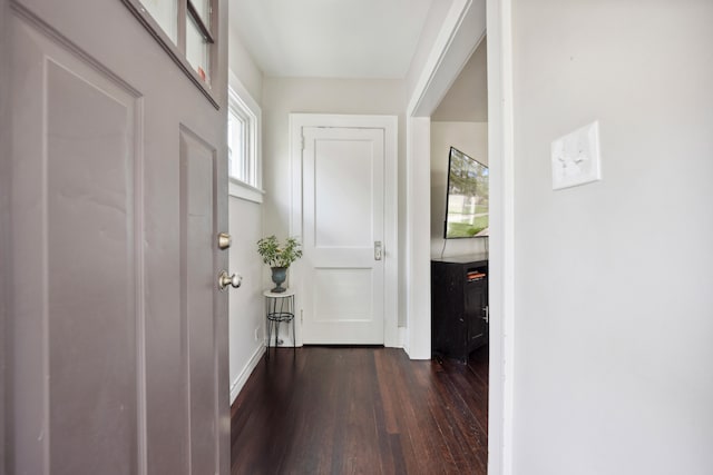 hall with dark wood-style flooring and baseboards