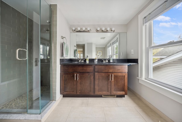 bathroom featuring double vanity, a shower stall, a sink, and tile patterned flooring