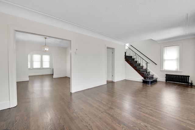 16560 Ashton Ave, Detroit, MI 48219 - unfurnished living room with radiator heating unit, stairs, dark wood-type flooring, and baseboards