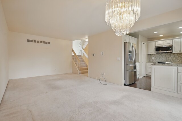 25030 Sherwood Cir, Southfield, MI 48075 - unfurnished living room with stairs, an inviting chandelier, visible vents, and dark colored carpet