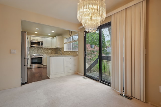 25030 Sherwood Cir, Southfield, MI 48075 - kitchen featuring appliances with stainless steel finishes, tasteful backsplash, a sink, a chandelier, and dark carpet