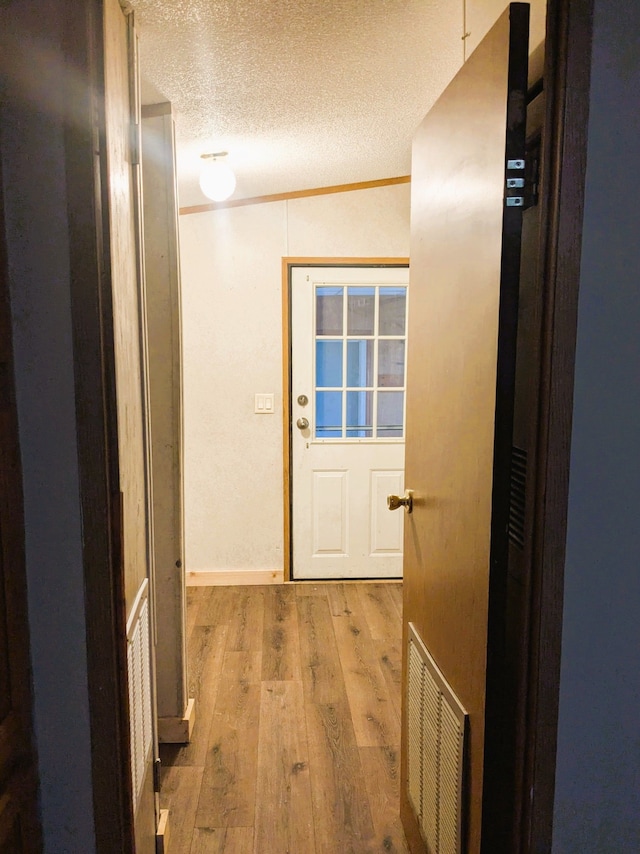 interior space featuring baseboards, a textured ceiling, visible vents, and wood finished floors