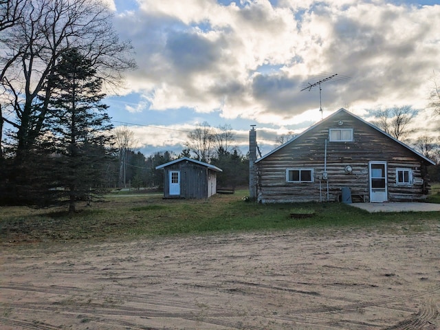 back of house featuring an outdoor structure, log siding, and a shed
