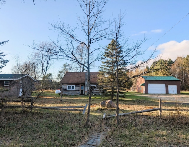 view of front of property with a detached garage, fence, an outdoor structure, and dirt driveway