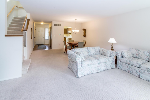 carpeted living area with visible vents, a notable chandelier, and stairway