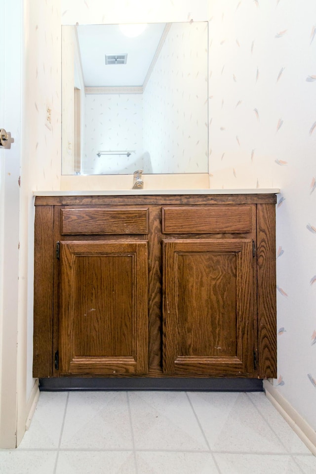 bathroom with baseboards, vanity, visible vents, and wallpapered walls
