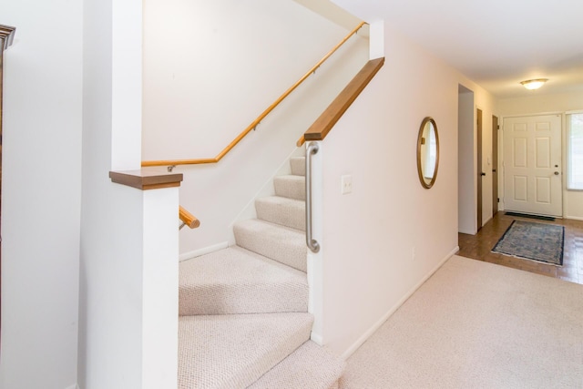 carpeted foyer featuring stairs and baseboards