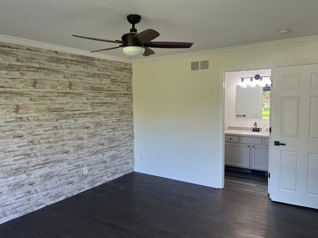 spare room with a sink, ceiling fan, an accent wall, dark wood finished floors, and ornamental molding