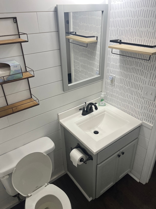 bathroom featuring toilet, vanity, tile walls, and wood finished floors