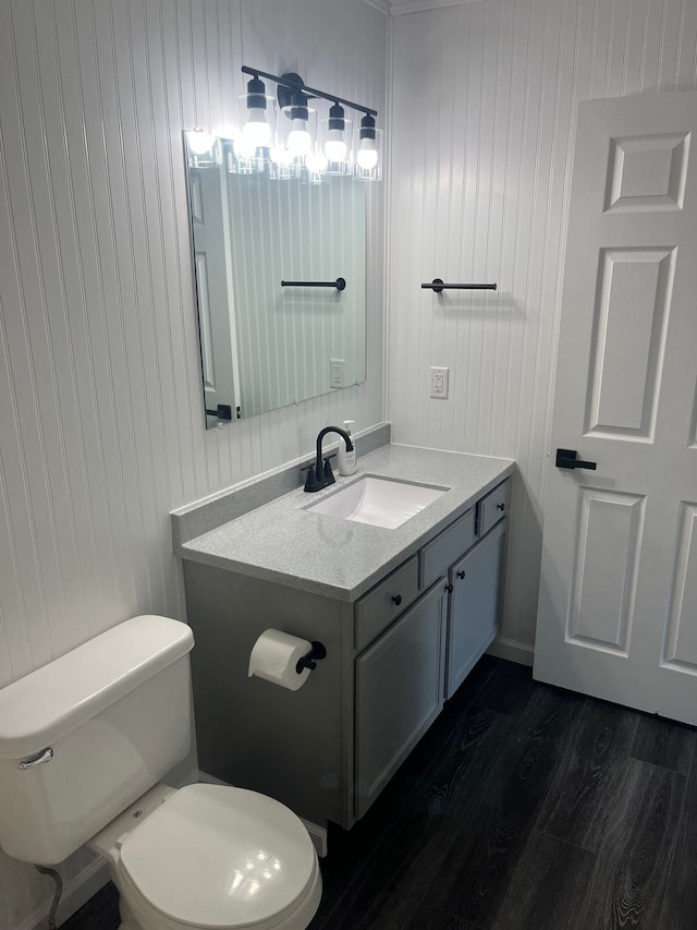 bathroom with wood finished floors, toilet, vanity, and wood walls