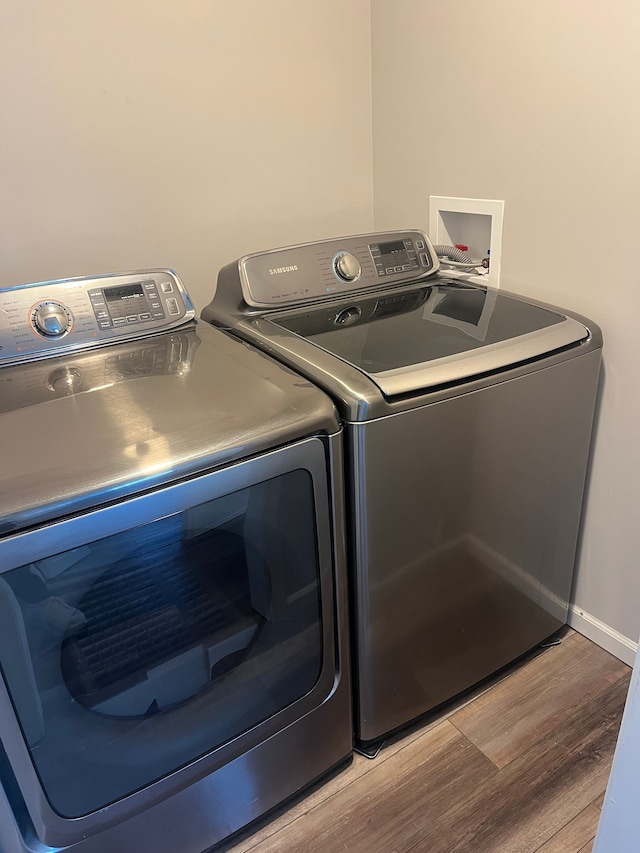 laundry area with washer and dryer and wood finished floors