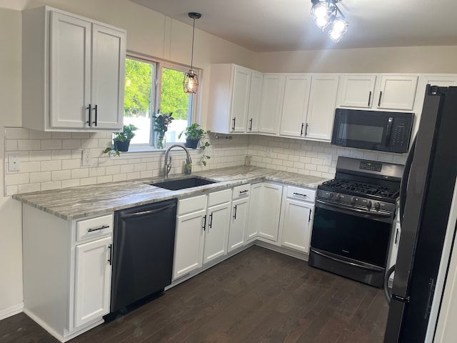 kitchen with black microwave, gas range, freestanding refrigerator, a sink, and dishwashing machine