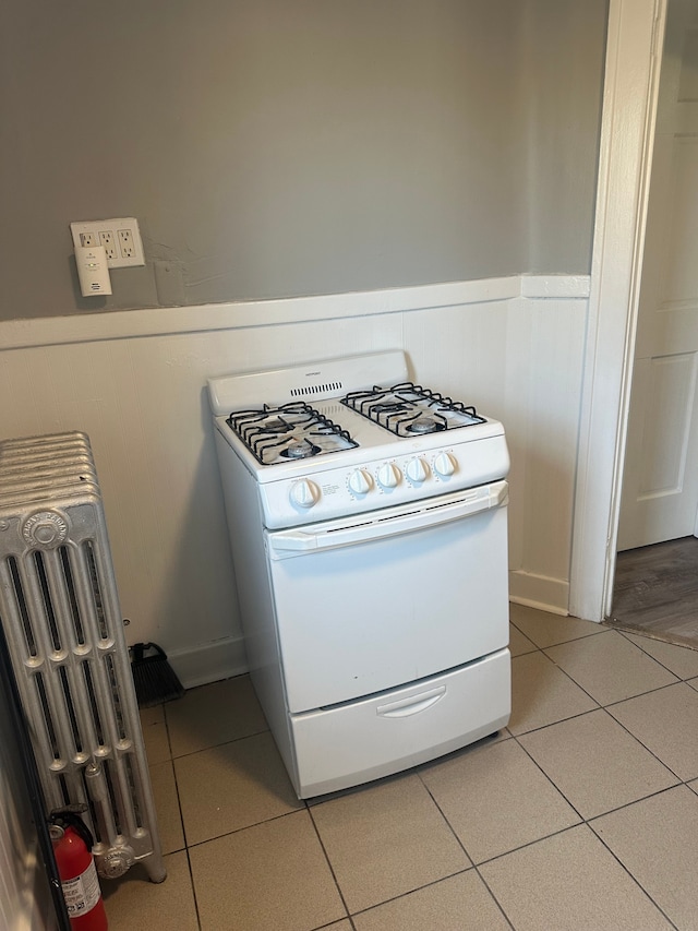 20 Thorpe St, Pontiac, MI 48341 - kitchen with white gas range oven, light tile patterned flooring, and a wainscoted wall