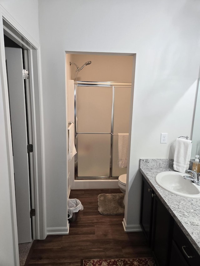 full bathroom featuring vanity, toilet, baseboards, a shower stall, and wood finished floors