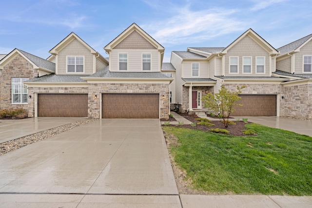 multi unit property with concrete driveway, a front yard, a garage, and stone siding