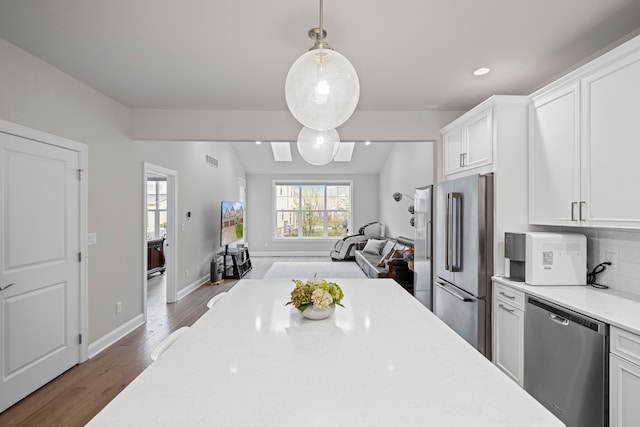 kitchen with pendant lighting, dark wood-style flooring, white cabinetry, open floor plan, and stainless steel appliances