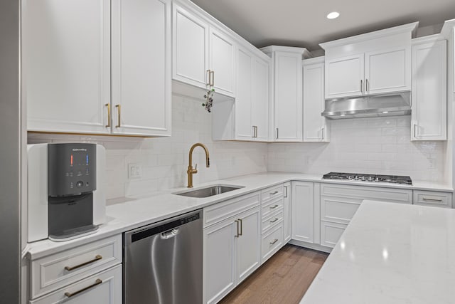 kitchen featuring a sink, white cabinets, dark wood-style flooring, under cabinet range hood, and appliances with stainless steel finishes