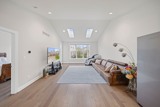 living room with a skylight, high vaulted ceiling, visible vents, light wood-style flooring, and baseboards