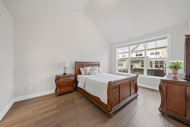 bedroom with dark wood finished floors, vaulted ceiling, and baseboards
