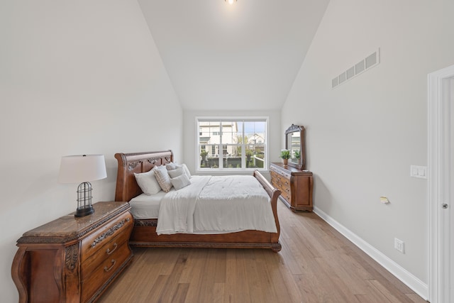 bedroom with light wood-type flooring, visible vents, baseboards, and high vaulted ceiling