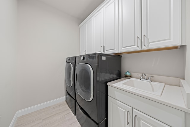 laundry room featuring baseboards, a sink, separate washer and dryer, and cabinet space