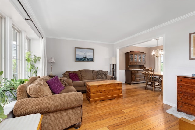 living area featuring crown molding, a notable chandelier, and light wood-style floors