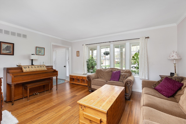 living room with crown molding, baseboards, visible vents, and light wood-style floors