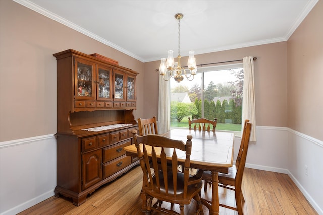 dining room featuring baseboards, ornamental molding, light wood finished floors, and a chandelier