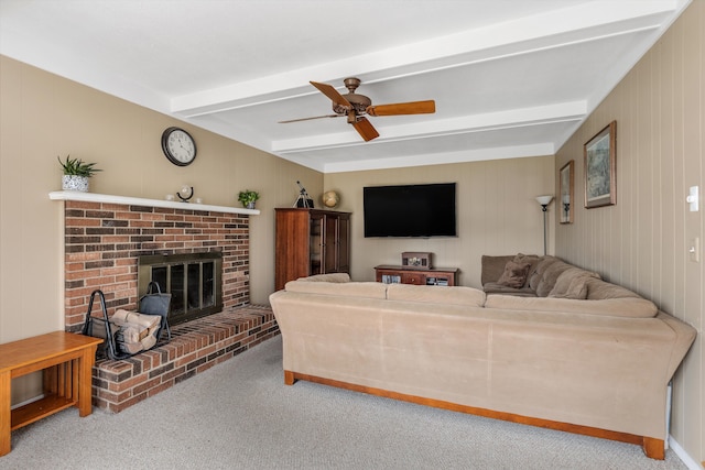 living room with a brick fireplace, carpet flooring, a ceiling fan, and beam ceiling