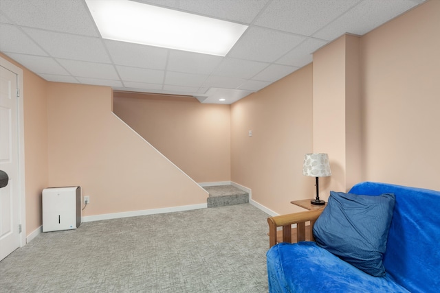 living area featuring baseboards, stairs, a paneled ceiling, and carpet