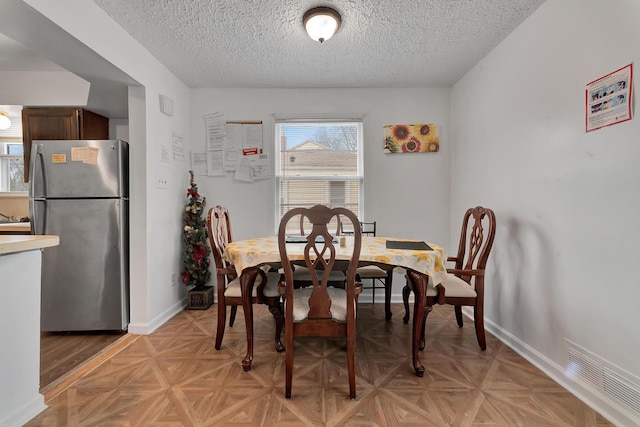 dining room featuring baseboards, a textured ceiling, and visible vents