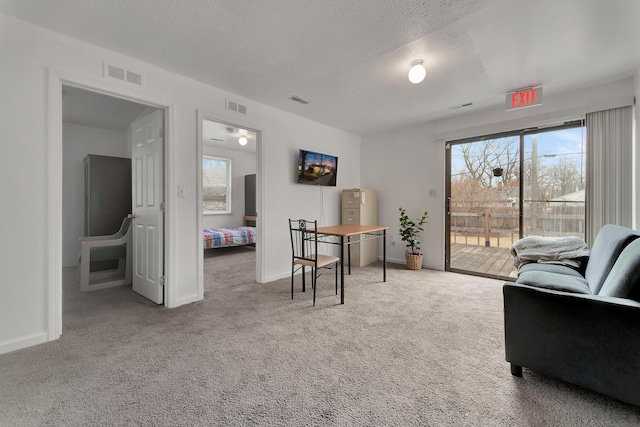 carpeted home office featuring baseboards, a textured ceiling, and visible vents