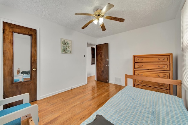 bedroom featuring a textured ceiling, visible vents, baseboards, and light wood-style floors