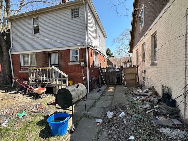 back of house featuring brick siding, fence, and a gate