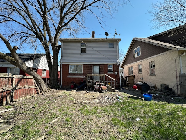rear view of property with fence, a chimney, and brick siding