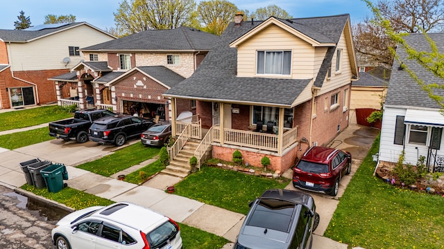 view of front of house with a porch, a shingled roof, a front lawn, and brick siding